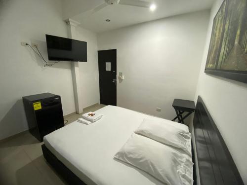 a bedroom with a white bed and a television at Hotel Malecon Puerto Berrio in Puerto Berrío