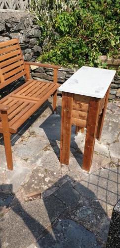 a wooden table and a wooden chair and a table and a table and a bench at Penbryn Holidays No 2 in Barmouth
