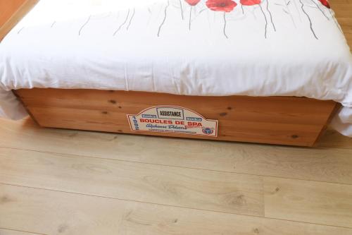 a bed with a sign on it sitting on a wooden floor at Au Temps de Spa - La Tour du Tonnelet in Spa