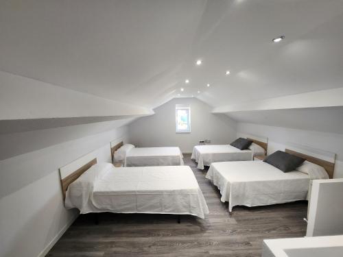 three beds in a room with white walls and wood floors at villa requian in Cacheiras