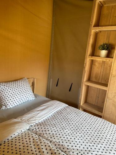 a bedroom with a bed and a wooden shelf at Glampingtent - Camping Botniahiem - Damwoude 