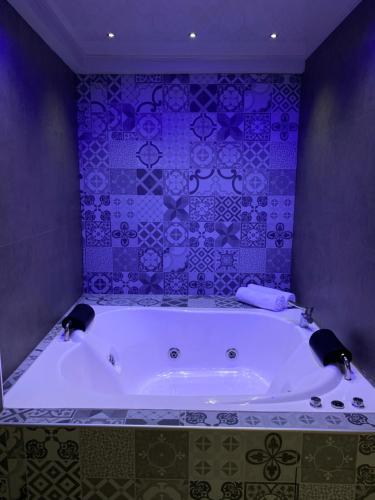 uma grande banheira na casa de banho com azulejos roxos em Izza Hotel em Cochabamba