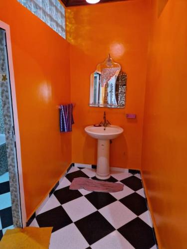 an orange bathroom with a sink and a checkered floor at REPOS SURF HOUSE 2 in Sidi Ifni