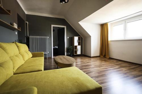 een woonkamer met een gele bank en een tafel bij Vila Benetton in Svitavy