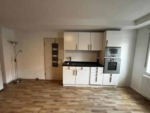 an empty room with a kitchen with white cabinets at WOHNEN AUF ZEIT in Göppingen