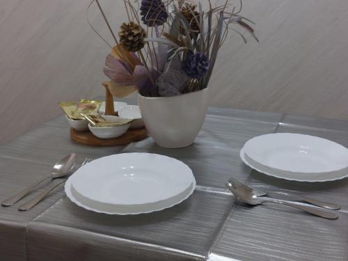 Dos platos blancos y tenedores y cucharas sobre una mesa en Studio Aleksandar, en Novi Pazar
