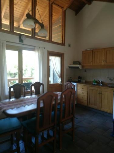 a kitchen with a wooden table and chairs and a table and a table at ABROJITOS in Villa La Angostura
