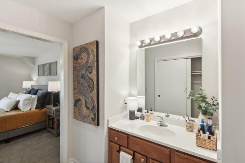 a bathroom with a sink and a mirror and a bed at Overland Park Condo, Close to Lakes and Parks! in Overland Park