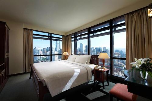 um quarto de hotel com uma cama grande e janelas grandes em Times Square Service Apartment , Kuala Lumpur em Kuala Lumpur