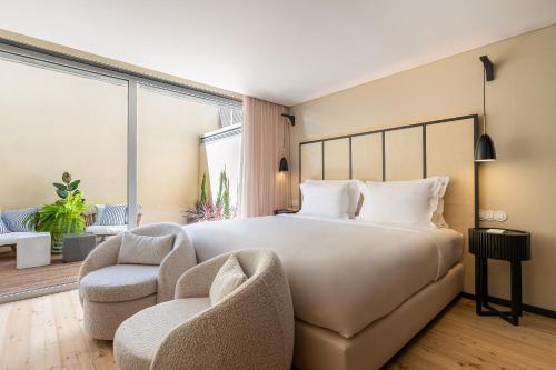 a bedroom with a large bed and two chairs at Artsy Cascais in Cascais