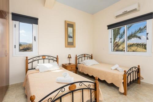 two beds in a room with two windows at Villa Kleopatra in Paphos
