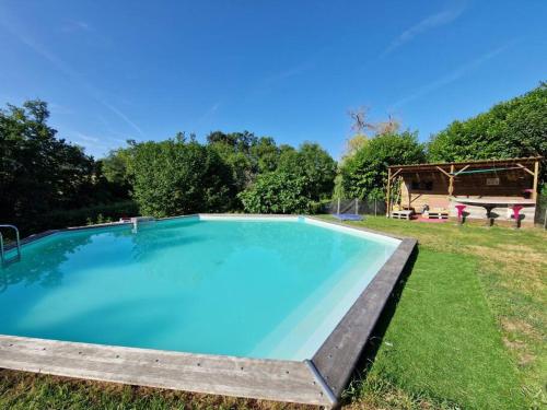 une grande piscine bleue dans une cour herbeuse dans l'établissement Maison de campagne avec piscine dans le bordelais, à Périssac