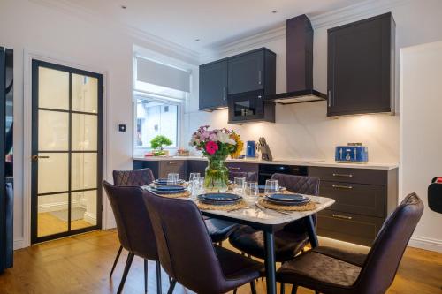 a dining room with a table with chairs and a kitchen at Canon Craig, Luxurious Lakeland stone Cottage in Bowness-on-Windermere