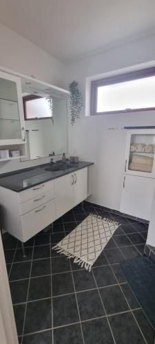 een witte keuken met een wastafel en een raam bij Family-friendly house close to Aarhus in Galten