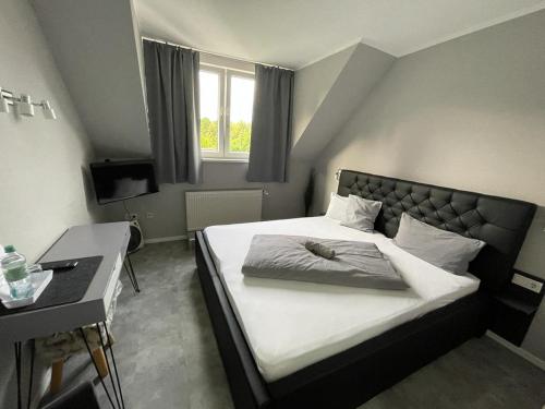 a bedroom with a bed and a desk and a window at Hotel Kellermann in Overath