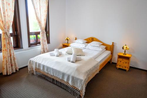 1 dormitorio con 1 cama con sábanas y almohadas blancas en White Dove Pension, en Miercurea-Ciuc