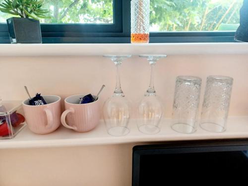 a shelf with wine glasses and cups on it at The Little Limes - Ensuite Double Room Own Entrance in Art Deco House in Kent