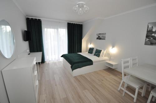 a bedroom with a bed and a table and a mirror at APARTAMENTY POD ŻAGLAMI MIELENKO in Mielenko