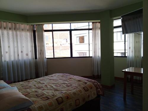 a bedroom with a bed and two large windows at Suma Qamaña in Copacabana
