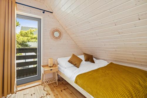 Cama en habitación con ventana en Natura Jantar - Całoroczne domy drewniane en Jantar