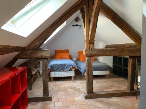 two beds in a attic room with wooden beams at Le Regisseur in Brissac-Quincé