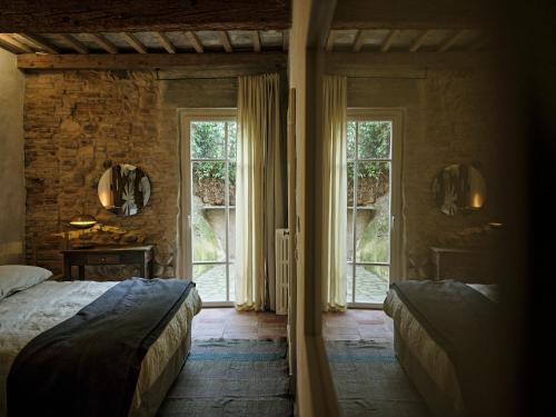 a bedroom with two beds in a room with windows at La Malvina ~5* centro storico~ Giardinetto privato in Santarcangelo di Romagna