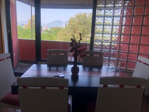a table with chairs and a vase with flowers on it at Grand Central Apartment LTH in Tirana