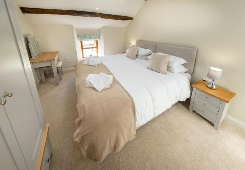 a bedroom with a large white bed and a desk at The Farmhouse, Sebergham, near Caldbeck in Sebergham