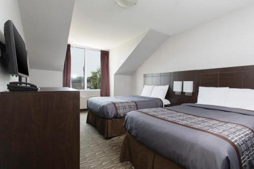 um quarto de hotel com duas camas e uma televisão de ecrã plano em Super 5 Inn em Mississauga