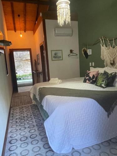 a bedroom with a large bed and a chandelier at Pousada Sítio das Pedras in Domingos Martins