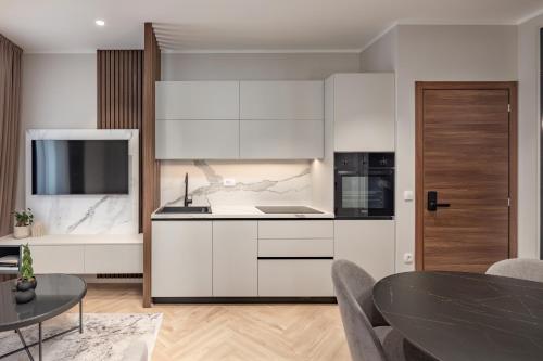 a kitchen with white cabinets and a black table at Upper Premium Apartments in Rijeka