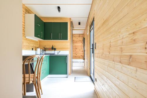 a kitchen with green cabinets and a wooden wall at Arche Siedlisko Hopkie 