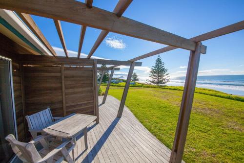 a wooden porch with a table and chairs on it at Tasman Holiday Parks - Papamoa Beach in Papamoa