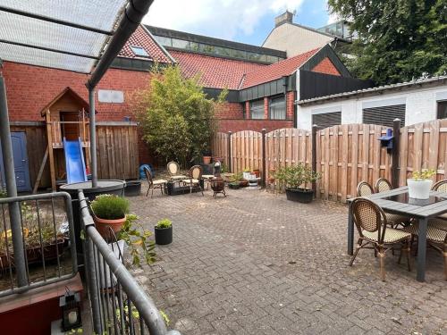 eine Terrasse mit Tischen, Stühlen und einem Zaun in der Unterkunft Hotel Wandsbek Hamburg in Hamburg