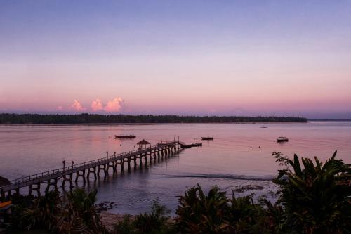 a dock on a body of water at sunset at The Oberoi Beach Resort, Lombok in Tanjung