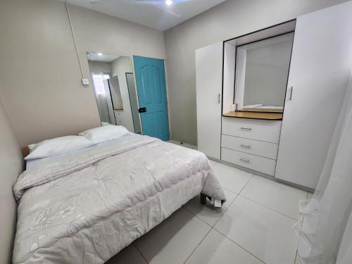 1 dormitorio con 1 cama con puerta azul y espejo en Home Away from Home en Suva