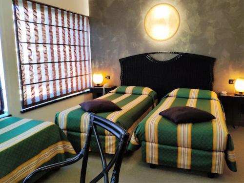 a bedroom with two beds and two chairs in it at Hotel Feel Inn Venice Airport Rooms in Campalto