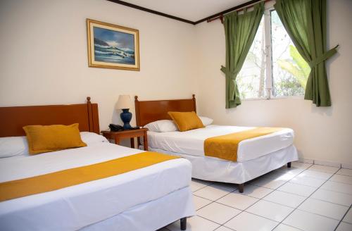 sypialnia z 2 łóżkami i oknem w obiekcie Hotel Villa Serena San Benito w mieście San Salvador