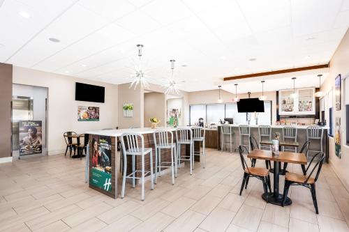 a restaurant with a bar with chairs and tables at Holiday Inn - Brownsville by IHG in Brownsville