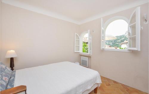 une chambre blanche avec un lit et deux fenêtres dans l'établissement Cozy Apartment In Roquebrune-Cap-Martin, à Roquebrune-Cap-Martin