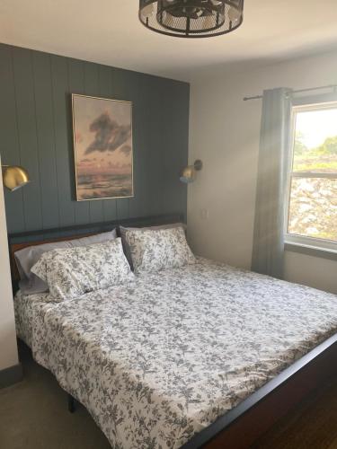 a bedroom with a bed with a comforter and a window at Unique waterfront house with private beach in Gananoque