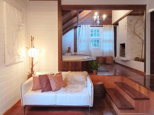 a living room with a white couch and a mirror at Espaço Verde Novo Chalés in Teresópolis