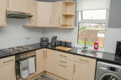 a kitchen with wooden cabinets and a sink and a window at Peaceful & Spacious Family Home In Eastbourne! in Eastbourne