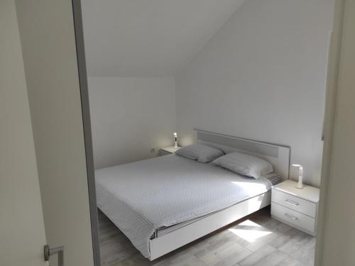 a white bedroom with a bed and a mirror at Veronika,Beppo,Coolio apartments in Mirce