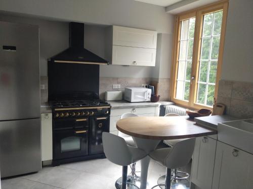 cocina con mesa, fogones y fregadero en Chalet les Pounets, en Damprichard