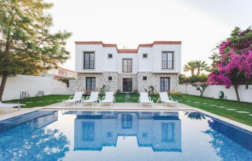 a villa with a swimming pool in front of a house at La Chance Otel Alaçatı in Alacati