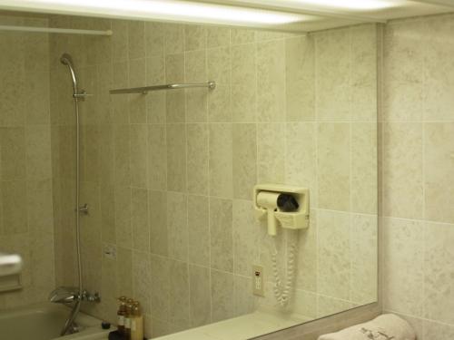 a bathroom with a shower with a phone on the wall at King Ambassador Hotel Kumagaya in Kumagaya