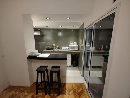 een keuken met 2 krukken en een aanrecht in een kamer bij Departamento totalmente reciclado con patio en Recoleta in Buenos Aires