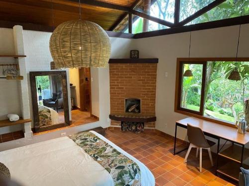 サン・ペードロ・ダ・セーハにあるCasAlê Come&Dormeのベッド、テーブル、暖炉が備わる客室です。