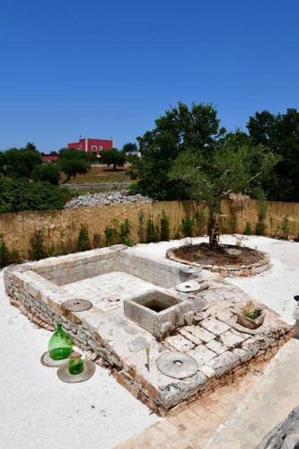 a stone garden with a fountain in the middle at Trulli di Titti - Luxury Country House in Castellana Grotte